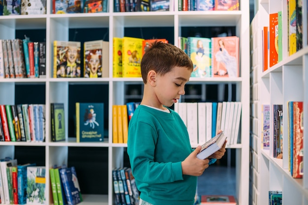 Um garotinho pega a prateleira de livros infantis na livraria