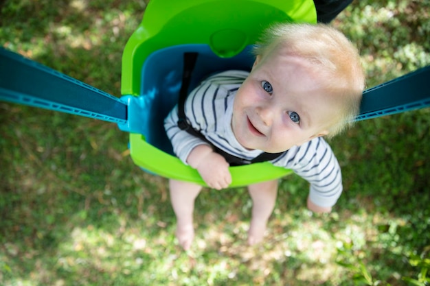 Um garotinho se divertindo brincando em um balanço debaixo de uma árvore em um jardim