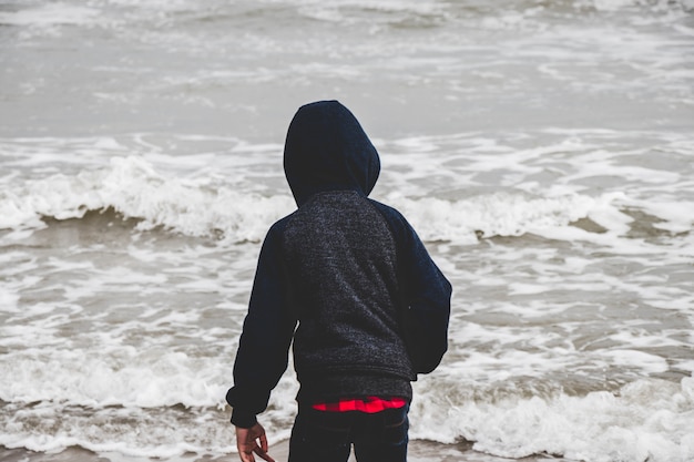 Foto um garotinho sozinho pelo oceano