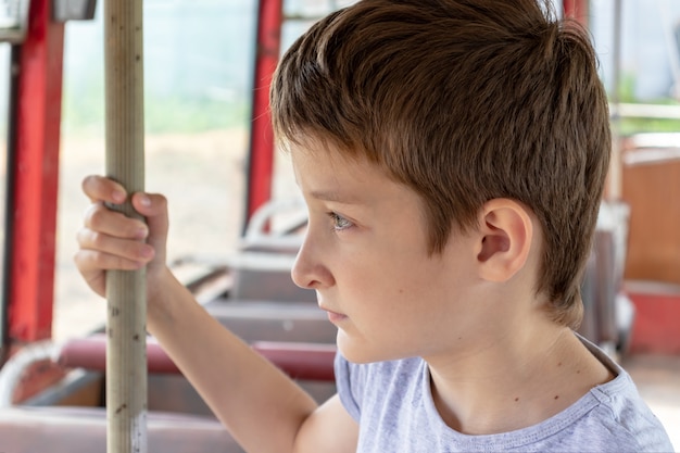 Um garoto de 10 anos andando em um velho ônibus vintage, ele está triste porque sua vida pobre e o ônibus se movendo em uma estrada suja