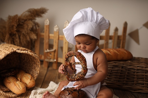 um garoto de pele escura em uma fantasia de cozinheiro tem um rolo