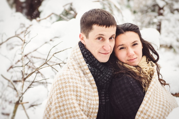 Um garoto e uma garota em roupas quentes e lenços em uma caminhada no bosque nevado e no campo