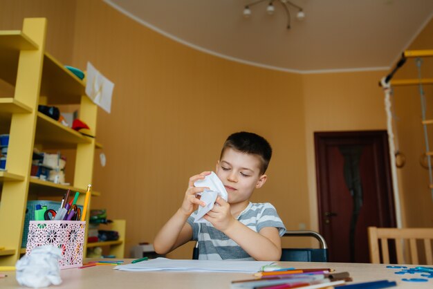 Um garoto em idade escolar faz a lição de casa em casa. Treinamento na escola