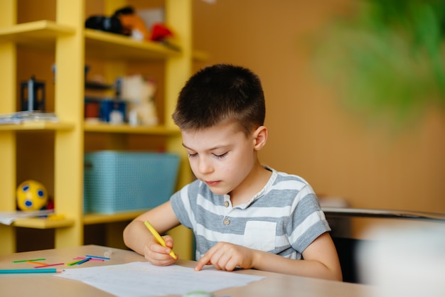 Um garoto em idade escolar faz a lição de casa em casa. Treinamento na escola