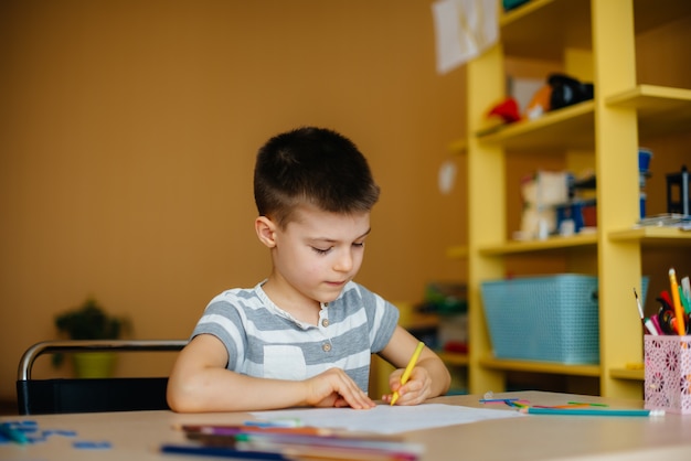 Um garoto em idade escolar faz a lição de casa em casa.