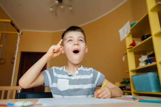 Um garoto em idade escolar faz a lição de casa em casa.