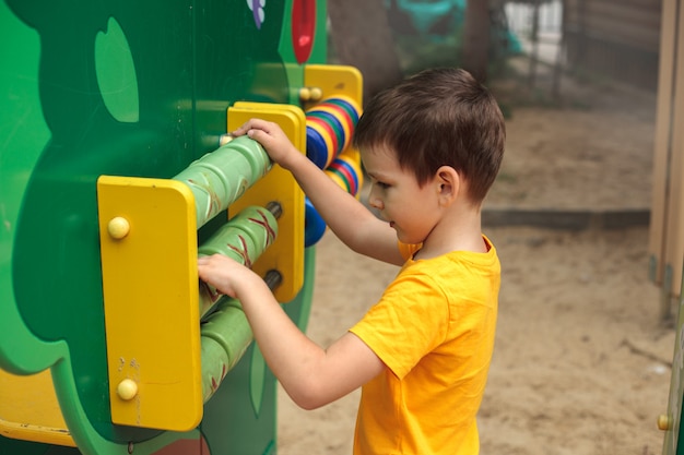 Um garoto no playground joga um jogo, vista traseira. Esportes infantis, lazer, hobbies.