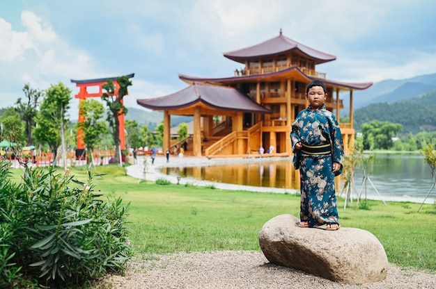 Um garoto vestido de quimono fica no meio de uma cidade modelo japonesa.