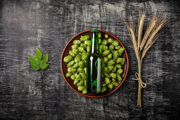 Um, garrafa cerveja, ligado, um, verde, pulo, em, um, prato, com, spikelets, e, pulo, folha, de, trigo, experiência, um, pretas, riscado, junta giz