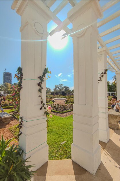 Foto um gazebo branco com uma vista de um parque e um edifício no fundo el rosedal