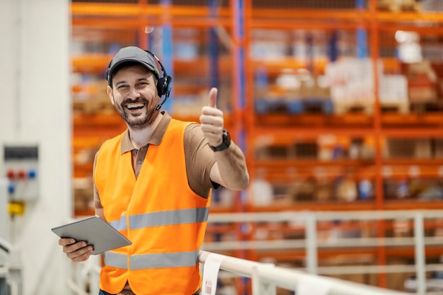 Um gerente de centro de entrega mostrando os polegares para cima e sorrindo para a câmera