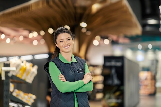 Um gerente de supermercado está orgulhoso e sorrindo para a câmera no mercado