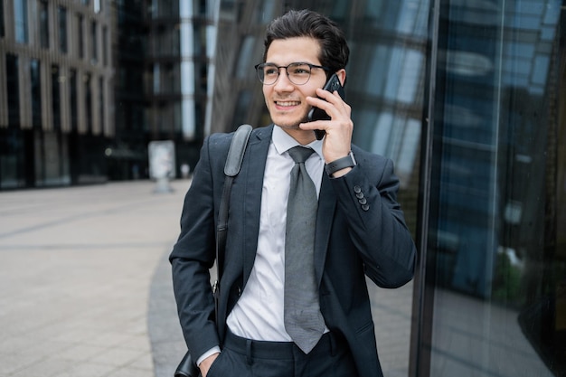 Um gerente masculino fala ao telefone em um terno de negócios vai trabalhar no escritório com uma maleta