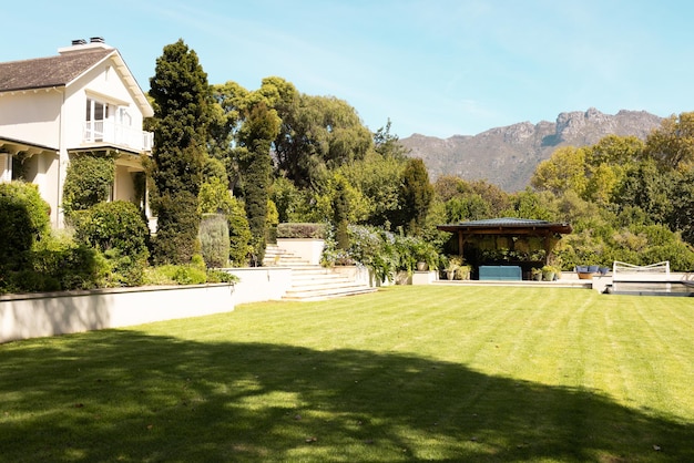 Um gramado verde exuberante se estende na frente de uma casa grande com montanhas atrás de casa.