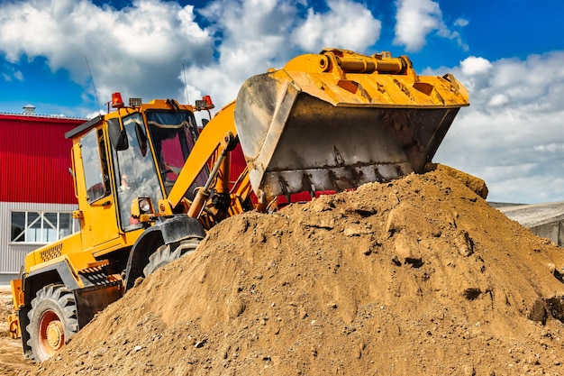 Um grande carregador frontal despeja areia em uma pilha em um canteiro de obras transporte de materiais a granel equipamento de construção transporte de carga a granel escavação