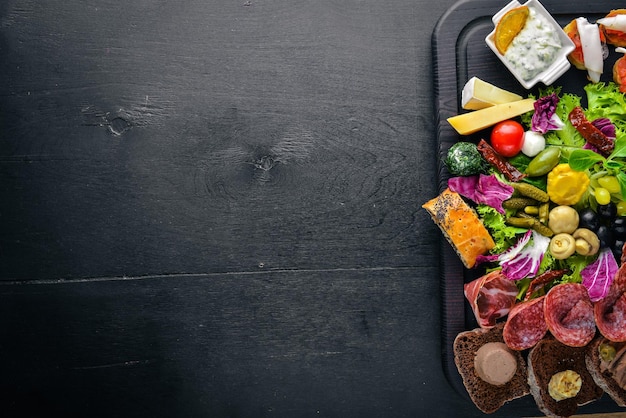 Um grande conjunto de cozinha italiana Carne de salsicha de queijo e legumes em conserva na placa de madeira Vista superior Espaço livre