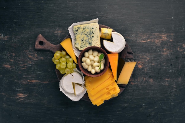 Um grande conjunto de queijos mozzarella blue cheese brie cheese maasdam vista superior em um fundo preto de madeira espaço livre para o seu texto