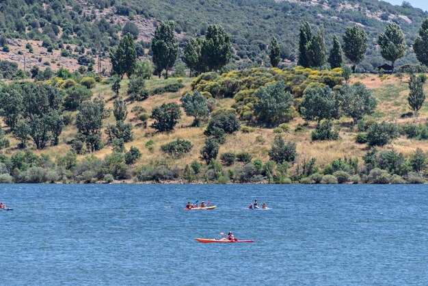 Um grande grupo de canoístas em um lago cercado por uma bela paisagem montanhosa
