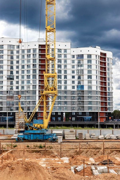 Um grande guindaste de torre em um canteiro de obras no contexto de uma casa monolítica moderna construção de habitação moderna engenharia industrial construção de habitação hipotecária