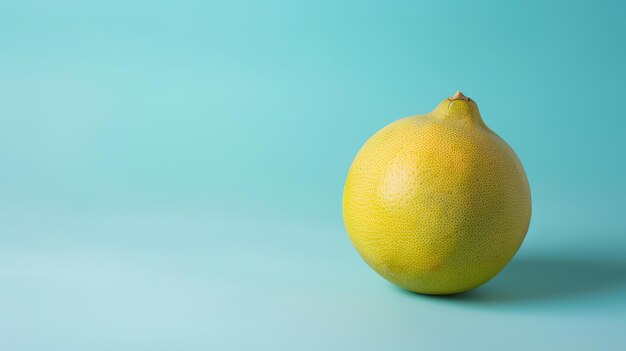 Um grande pomelo maduro está sentado em uma mesa azul O pomelo é redondo e amarelo com uma pele ligeiramente irregular