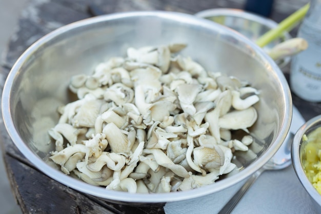 Um grande prato de cogumelos frescos brancos para cozinhar na cozinha de verão