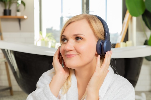 um grande retrato com as mãos de uma jovem loira sorridente com fones de ouvido ouvindo música