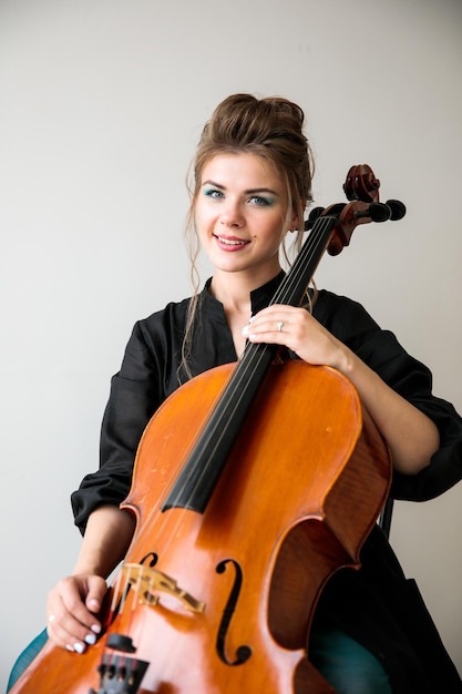 Um grande retrato de uma menina com um violoncelo um violoncelista senta-se com um violoncelo e olha para a câmera