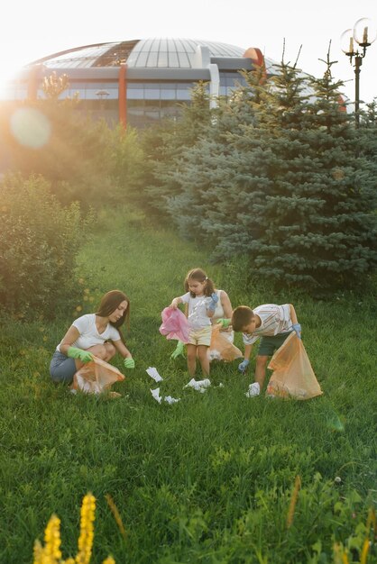 Um grupo de adultos e crianças juntos ao pôr do sol está envolvido na coleta de lixo no parque Reciclagem de resíduos de cuidados ambientais Separando lixo