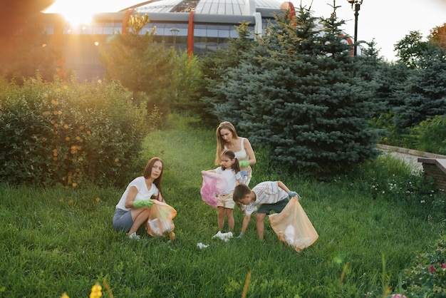 Um grupo de adultos e crianças juntos ao pôr do sol está envolvido na coleta de lixo no parque Reciclagem de resíduos de cuidados ambientais Separando lixo