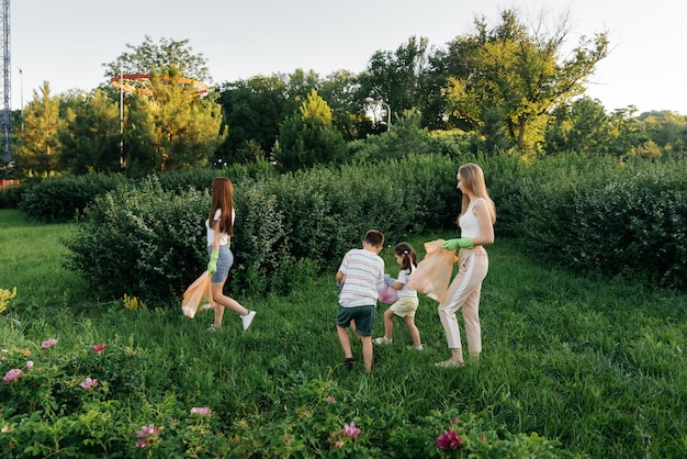 Um grupo de adultos e crianças juntos ao pôr do sol está envolvido na coleta de lixo no parque Reciclagem de resíduos de cuidados ambientais Separando lixo