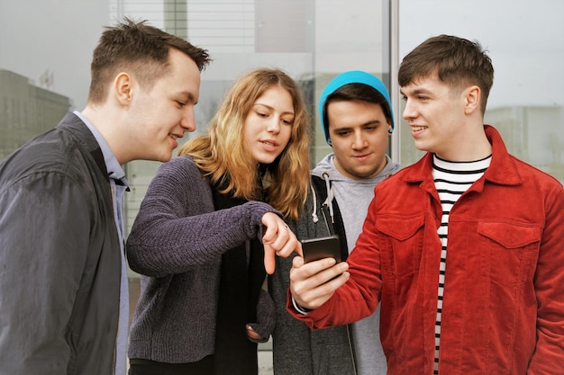 Foto um grupo de amigos adolescentes discutindo alguns conteúdos de telefones celulares