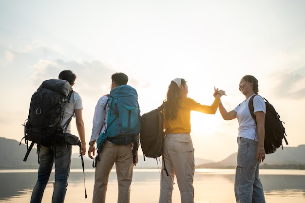 Um grupo de amigos asiáticos mochilando e caminhando para piquenique e acampamento perto do lago