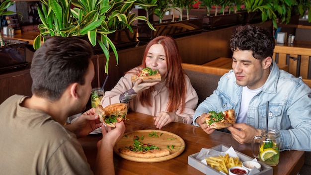 Um grupo de amigos descansando em um bar. Comendo, bebendo, comida na mesa. Amizade