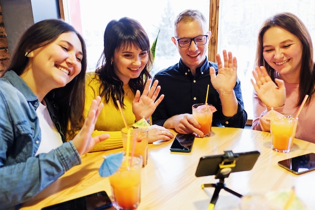 Foto um grupo de amigos faz uma videochamada e cumprimenta a outra pessoa