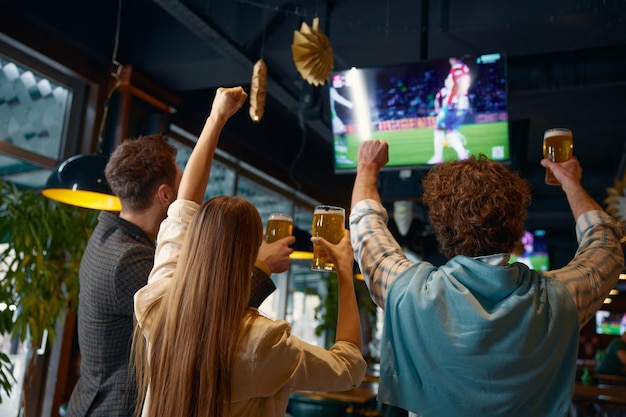 Um grupo de amigos felizes a ver um jogo de futebol na televisão num pub.