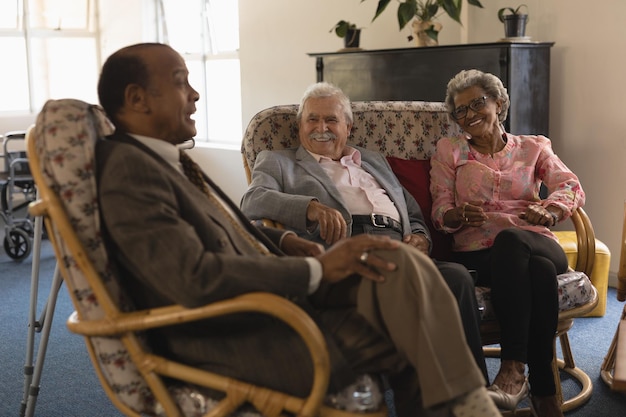 Foto um grupo de amigos idosos a interagir uns com os outros num lar de idosos.
