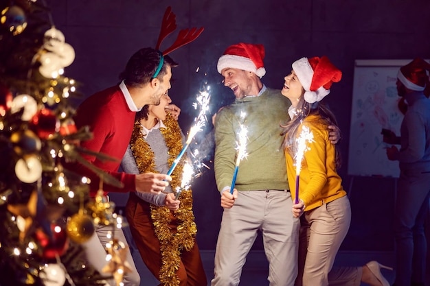 Um grupo de amigos multiculturais felizes parados no escuro segurando fogos de artifício na véspera de Ano Novo