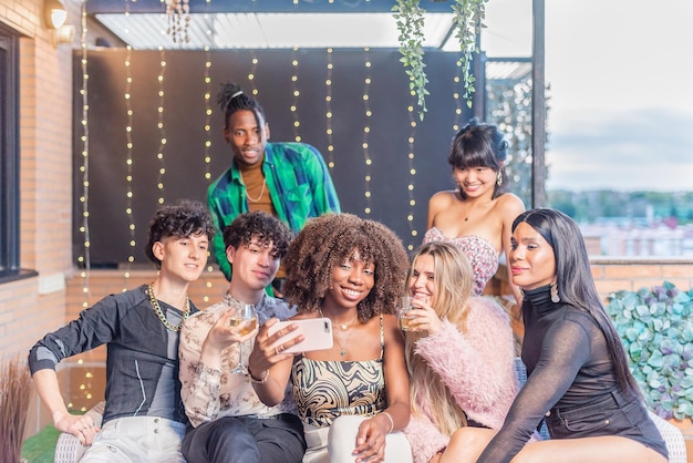 Um grupo de amigos multiétnicos tirando uma selfie em um terraço enquanto bebe