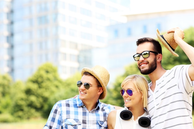 Um grupo de amigos olhando algo no parque em frente a edifícios modernos