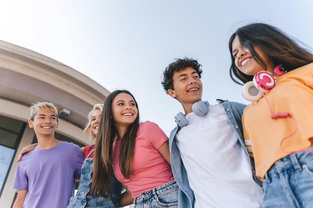 Foto um grupo de amigos sorridentes adolescentes vestindo roupas casuais coloridas falando andando na rua