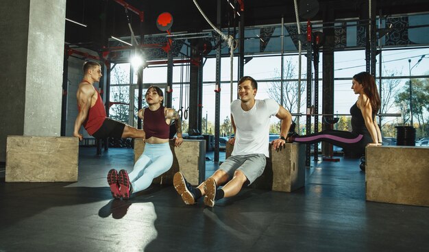 Um grupo de atletas musculosos fazendo exercícios no ginásio. Ginástica, treino, flexibilidade de treino de fitness. Estilo de vida ativo e saudável, juventude, musculação. Treinamento com caixas de salto esportivas.