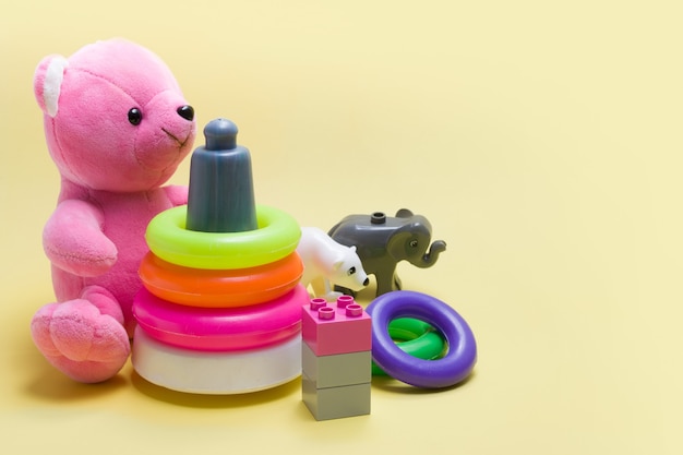 Um grupo de brinquedos infantis em um fundo colorido. Ursinho de pelúcia, pirâmide e construtor para desenvolvimento de bebês