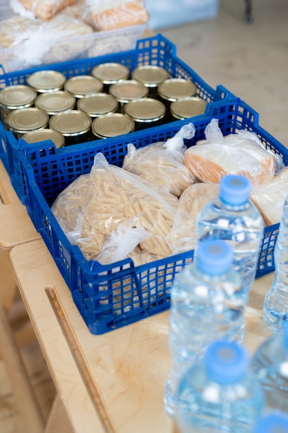 Um grupo de caixas de plástico com produtos alimentícios e garrafas de água na mesa