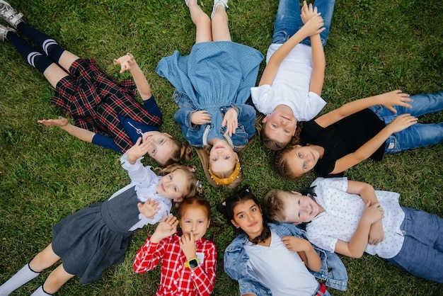 Um grupo de crianças em idade escolar deita na grama em círculo e se diverte