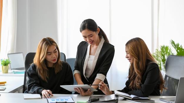 Um grupo de empresárias asiáticas felizes trabalhando juntas em sua apresentação de projeto no escritório.