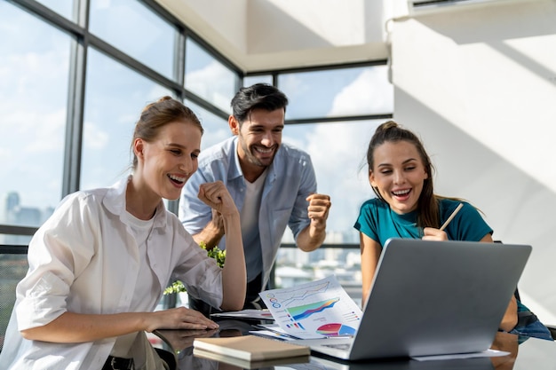 Um grupo de empresários felizes celebram o sucesso do seu projecto. Uma equipa de empresários profissionais ganha e orgulha-se do seu projecto num escritório moderno. Trabalho em equipa bem sucedido. Colegas felizes no local de trabalho.