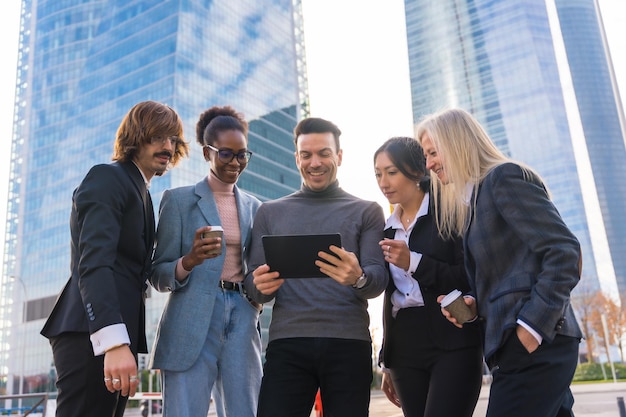 Um grupo de empresários multiétnicos em um parque empresarial olhando para um tablet