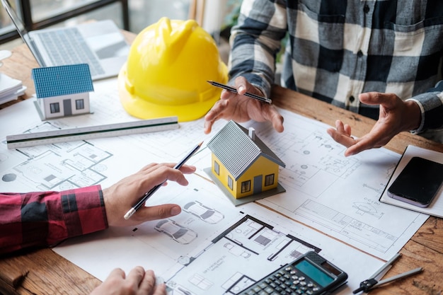 Um grupo de engenheiros trabalhando em planos e modelos de casas em suas mesas.