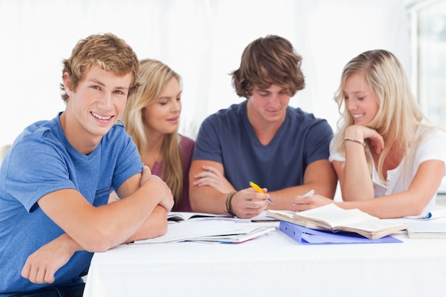 Um grupo de estudantes sentados juntos enquanto todos estudam enquanto um senta um pouco