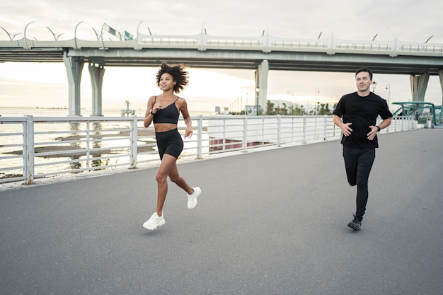 Um grupo de homens e mulheres fitness na rua Pessoas amigos atletas correm por saúde e felicidade